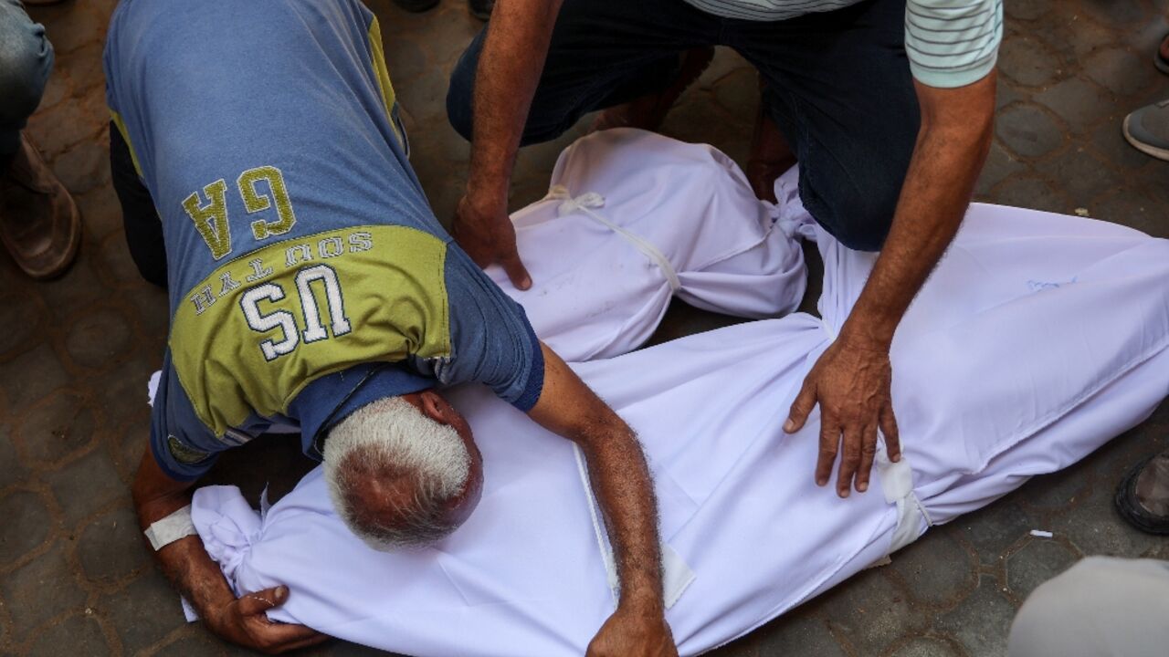Men weep over the bodies of victims of an Israeli strike which hit the Mustafa Hafez School that was sheltering Palestinians displaced by the war