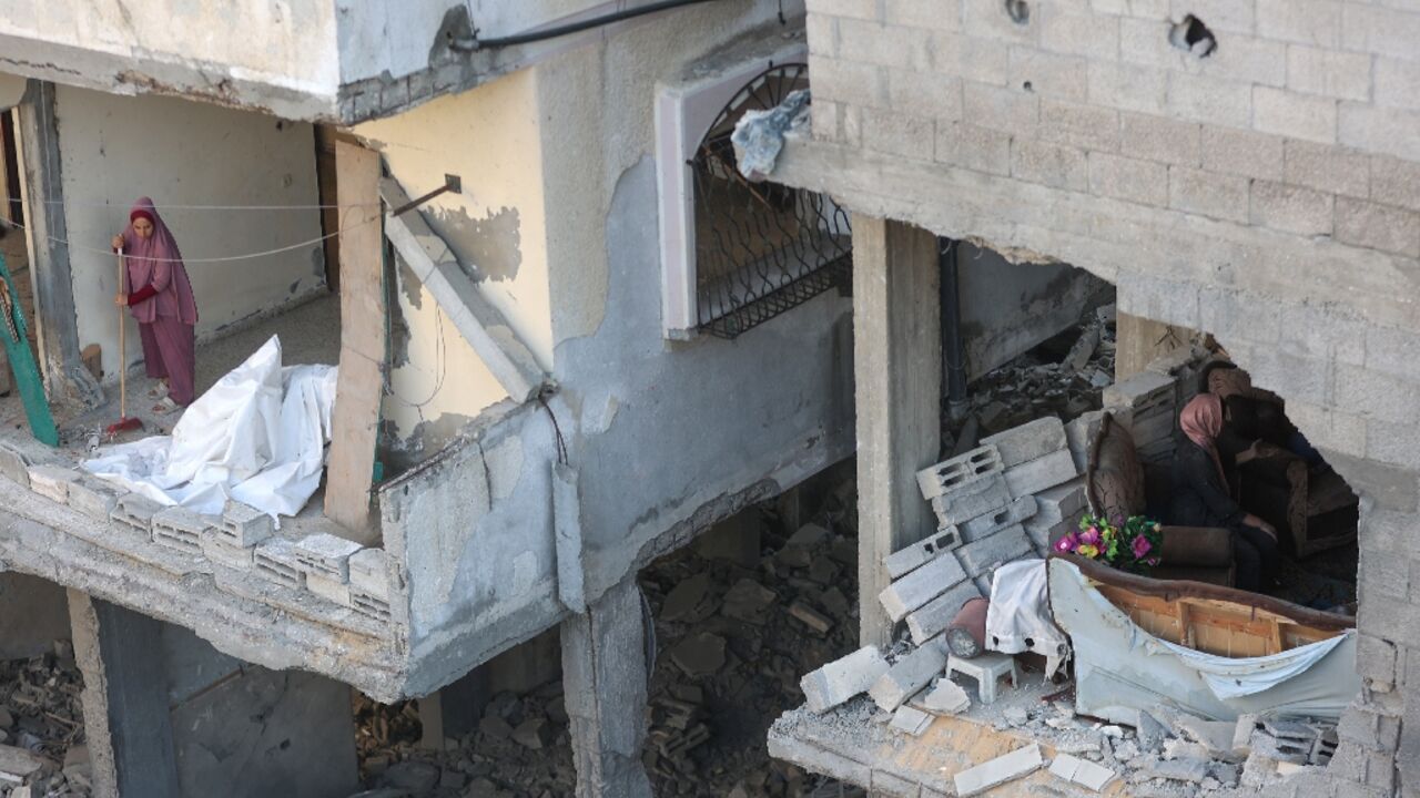 A Palestinian woman clears debris from her home as he neighbour inspects the damage after an Israeli strike on the Al-Shati refugee camp, west of Gaza City, on July 9, 2025