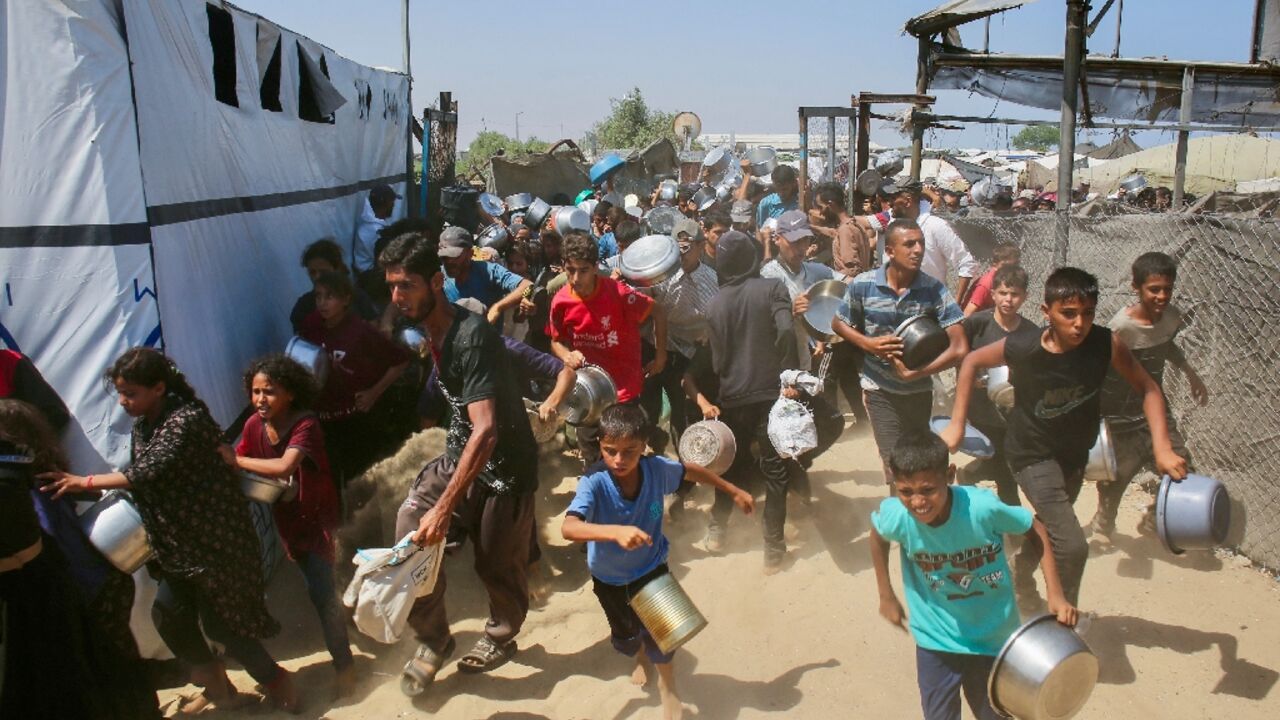 Palestinians rush to queue at a charity kitchen in Gaza, where the population has been experiencing acute food shortages for months