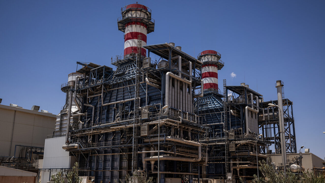 Workers walk past the gas turbine and heat recovery system of Syria's largest power plant on June 12, 2025 in Deir Ali, Syria. 