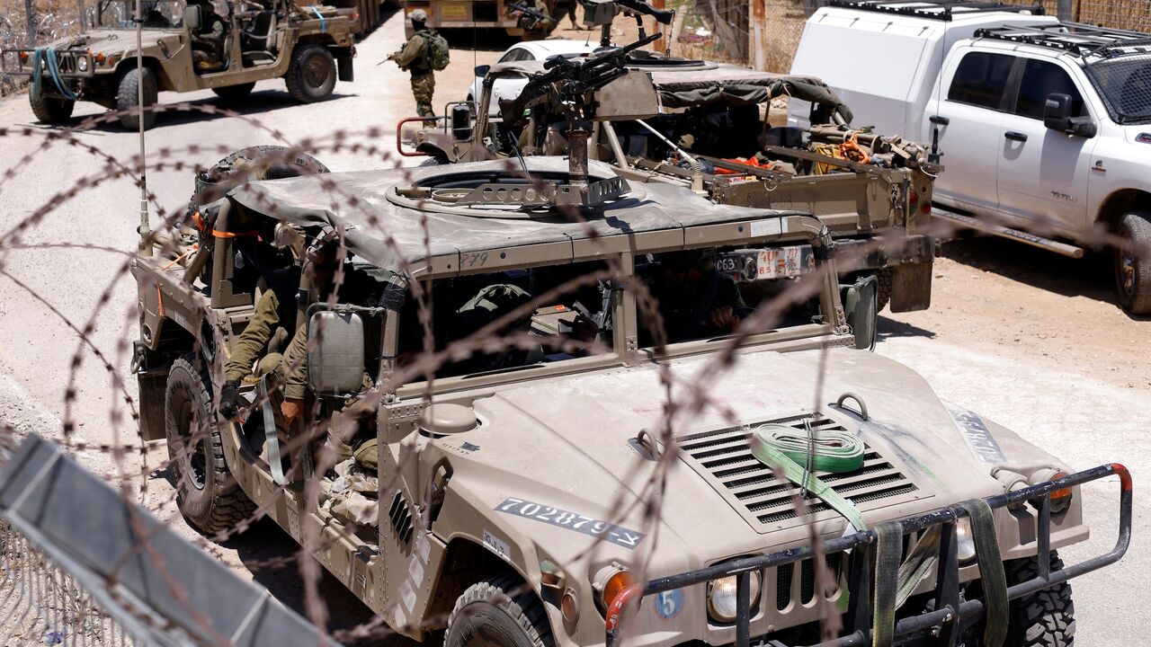 Israel military vehicles drive along the border fence with Syria, near the town of Majdal Shams, in the Israeli-annexed Golan Heights, July 17, 2025.