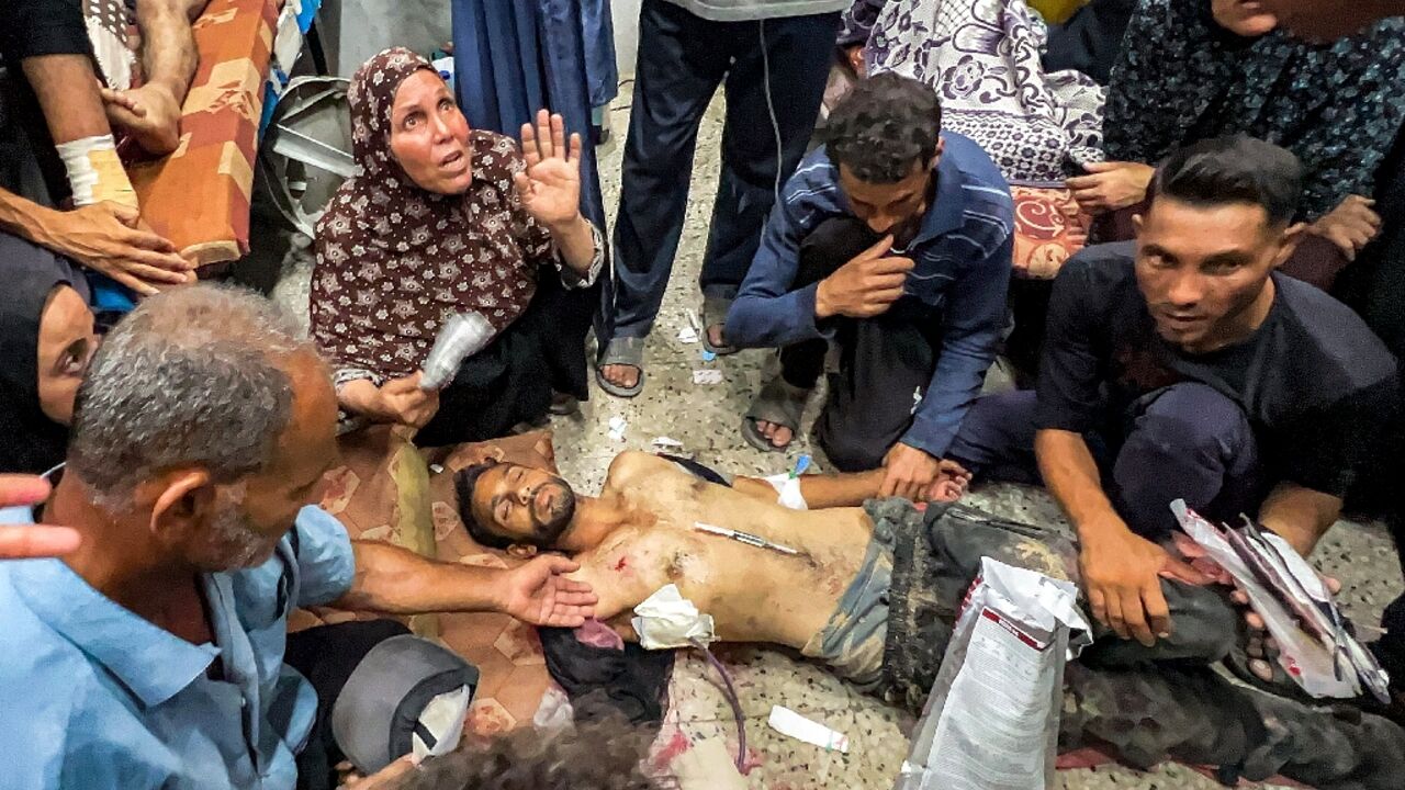People gathered around one of the people shot while waiting for aid trucks entering Gaza on Thursday
