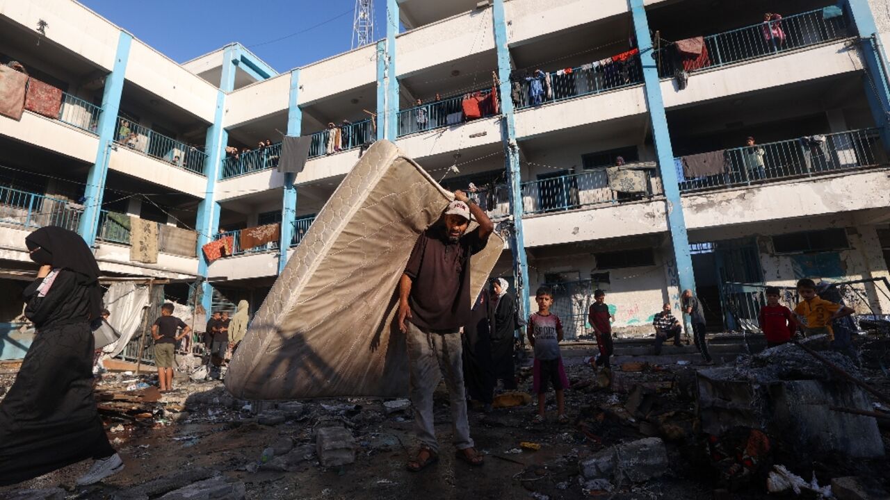 A Palestinian man carries a mattress after an Israeli strike that hit a school sheltering displaced Palestinians in the Al-Bureij camp in central Gaza