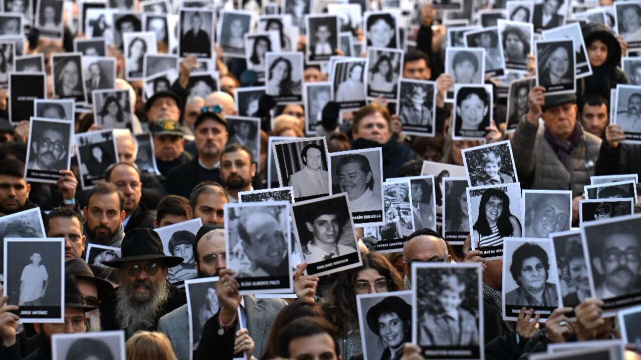 People hold pictures of victims on the 31st anniversary of the AMIA bombing in Buenos Aires