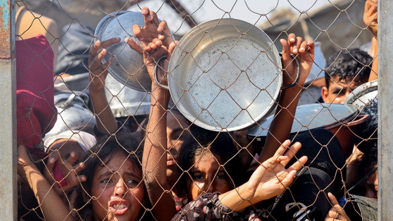 Palestinians, mostly children, push to receive a hot meal at a charity kitchen in the Mawasi area of Khan Yunis in the southern Gaza Strip on July 22, 2025
