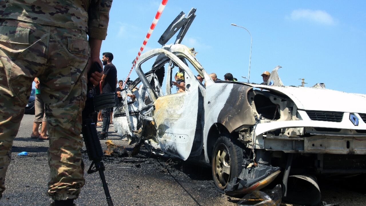 Lebanese army soldiers inspect the wreckage of a vehicle hit it an Israeli strike on southern Lebanon