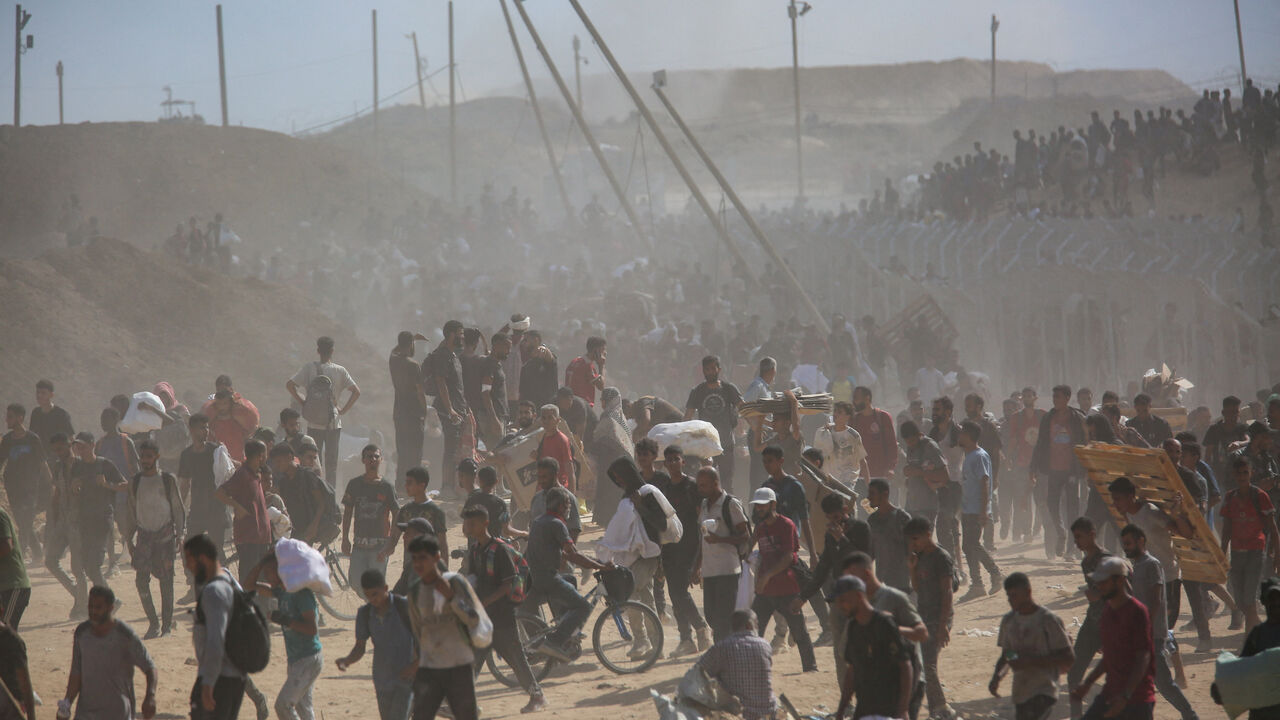 FILE PHOTO: Palestinians carry aid supplies which they received from the U.S.-backed Gaza Humanitarian Foundation, in the central Gaza Strip, July 31, 2025. REUTERS/Stringer/File Photo