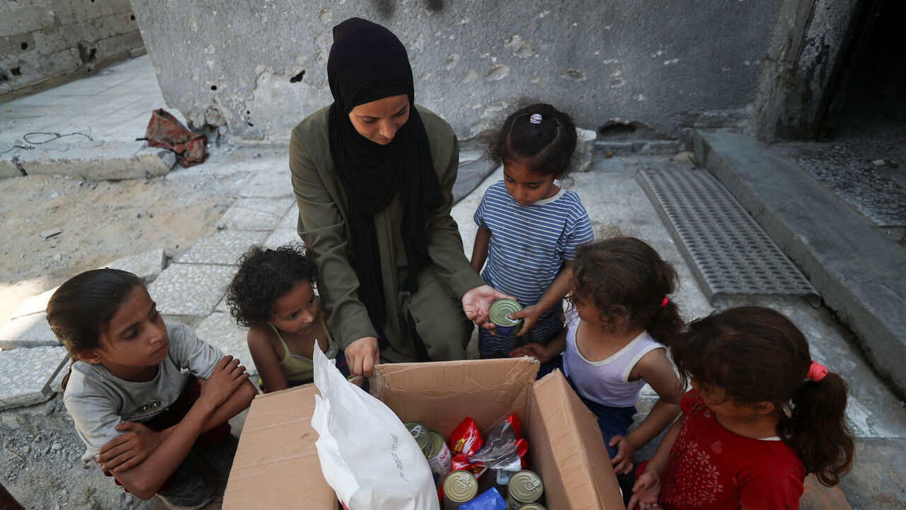 Amal Abu Assi, a Palestinian mother of three, displays the contents of an airdropped food parcel she received, in Gaza City, July 28, 2025. REUTERS/Mahmoud Issa
