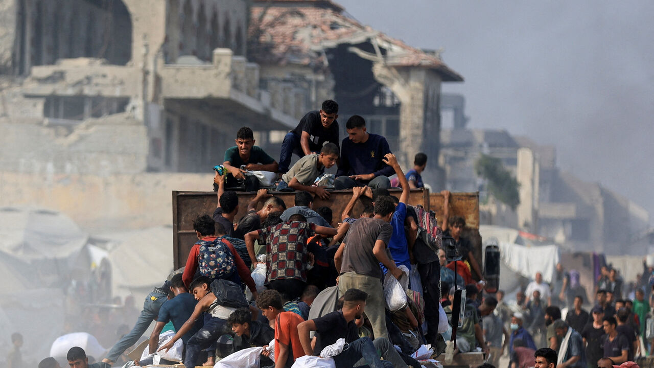 FILE PHOTO: Palestinians ride on a truck as they collect aid supplies that entered Gaza through Israel, in Beit Lahia, in the northern Gaza Strip August 10, 2025. REUTERS/Dawoud Abu Alkas/File Photo