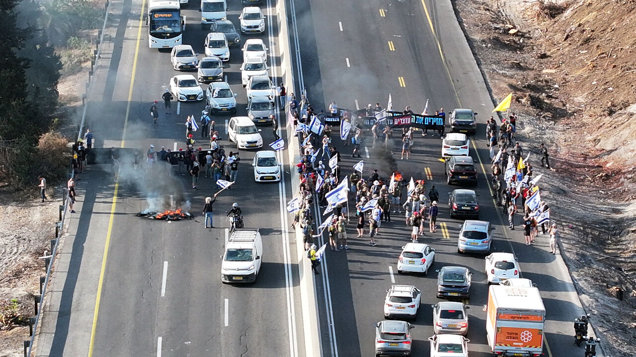 A drone photo shows protesters standing next to burning tires as they block Israel's main highway connecting Jerusalem and Tel Aviv near Latrun, Israel, after families of hostages have called for a nationwide strike to demand the return of all hostages and an end to the war in Gaza, August 17, 2025. REUTERS/Stringer