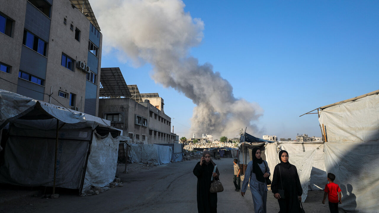 Palestinians make their way as smoke rises following an Israeli strike, in Gaza City, August 24, 2025. REUTERS/Dawoud Abu Alkas