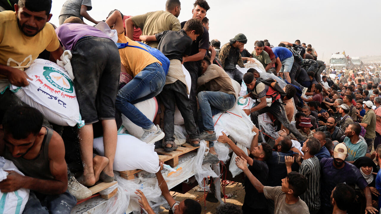 FILE PHOTO: Palestinians scramble to collect aid supplies from trucks that entered through Israel, in Khan Younis, southern Gaza Strip, August 12, 2025. REUTERS/Hatem Khaled/File Photo