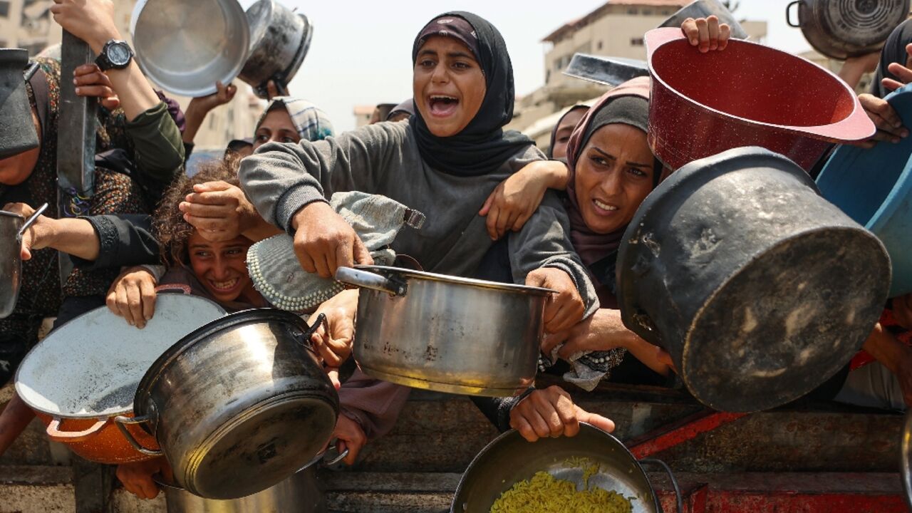 Palestinians scramble to receive cooked meals from an aid distribution centre in Gaza City.