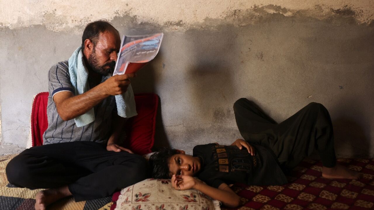 An Iraqi man fans his son at his home south of Hilla amid the heat of August