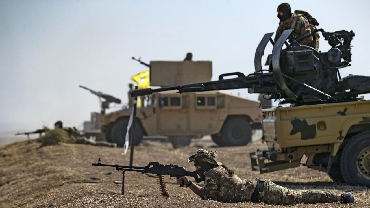 A fighter of the Syrian Democratic Forces (SDF) aims a machine gun while lying prone during a joint military exercise with forces of the US-led "Combined Joint Task Force-Operation Inherent Resolve" coalition against the Islamic State (IS) group in the countryside of the town of al-Malikiya (Derik in Kurdish) in Syria's northeastern Hasakah province on Sept. 7, 2022.