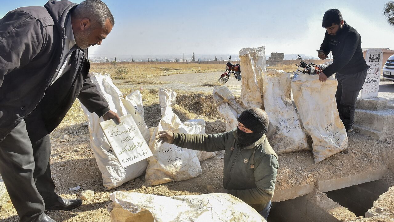 Workers package human remains recovered from the mass grave in Damascus, Syria, on Dec. 17, 2024. 