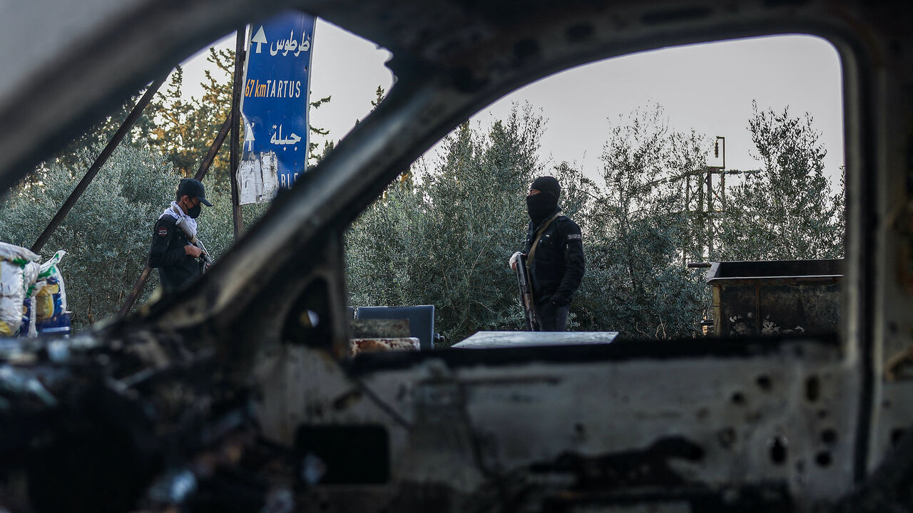 Security forces loyal to the interim Syrian government stand guard at a checkpoint previously held by supporters of deposed president Bashar al-Assad, in the town of Hmeimim, in the coastal province of Latakia, on March 11, 2025.  