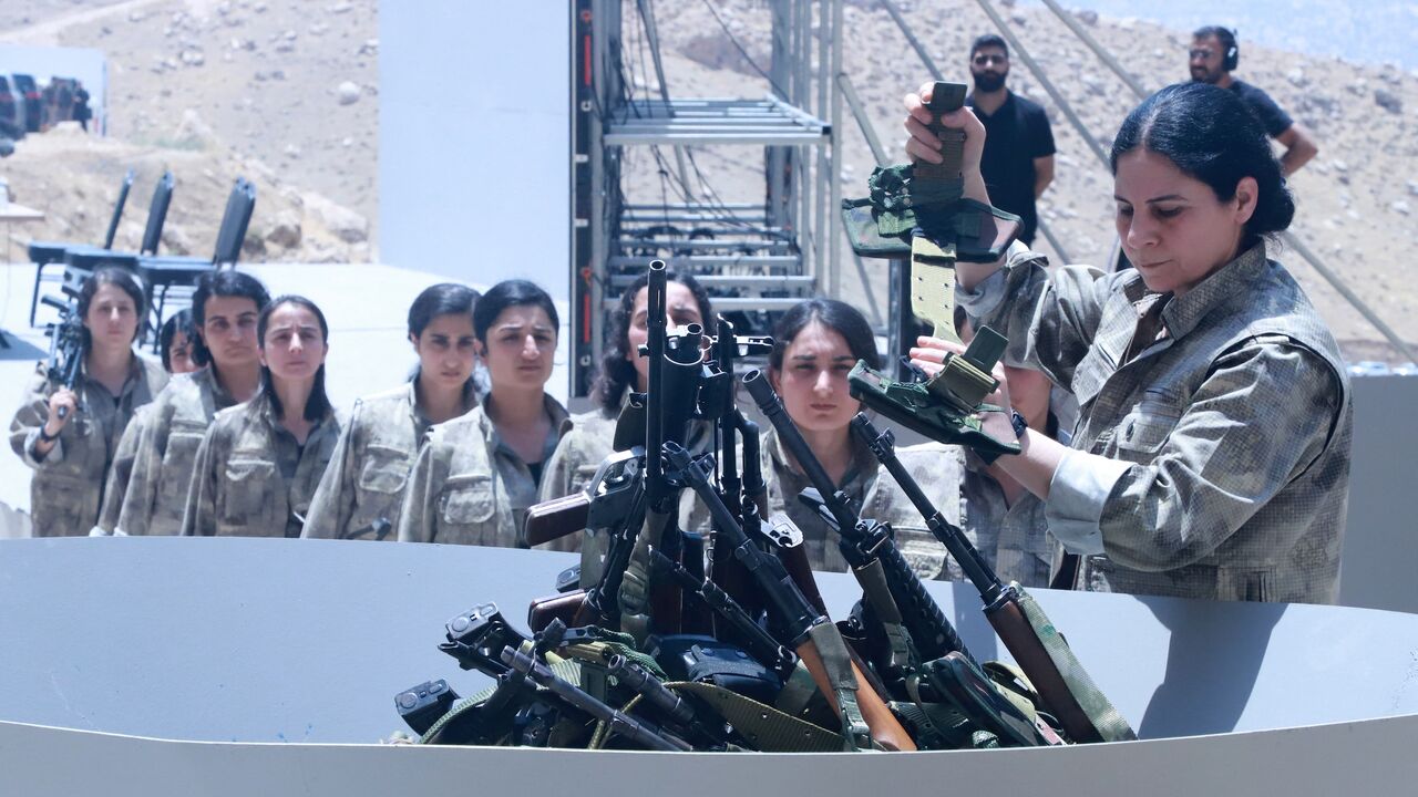 Fighters with the Kurdistan Workers Party (PKK) line up to put their weapons into a pit during a ceremony in Sulaimaniyah, in Iraq's autonomous Kurdistan region, on July 11, 2025.