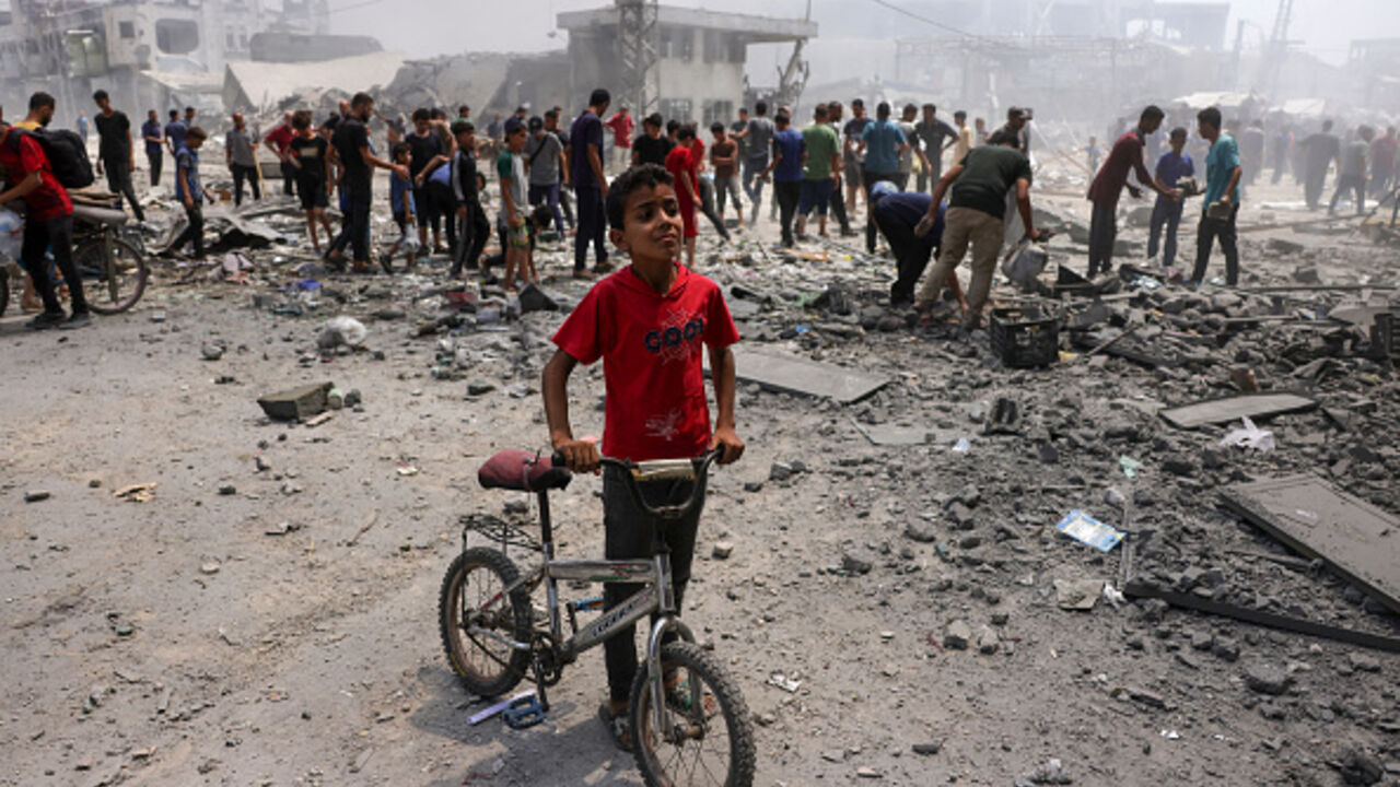 A young boy stands next to his bicycle as Palestinians check the devastation following an Israeli strike that hit Gaza City's southern al-Zeitoun neighbourhood on August 8, 2025. Israel's military will "take control" of Gaza City under a new plan approved by Prime Minister Benjamin Netanyahu's security cabinet, touching off a wave of criticism Friday from both inside and outside the country. (Photo by BASHAR TALEB / AFP) (Photo by BASHAR TALEB/AFP via Getty Images)