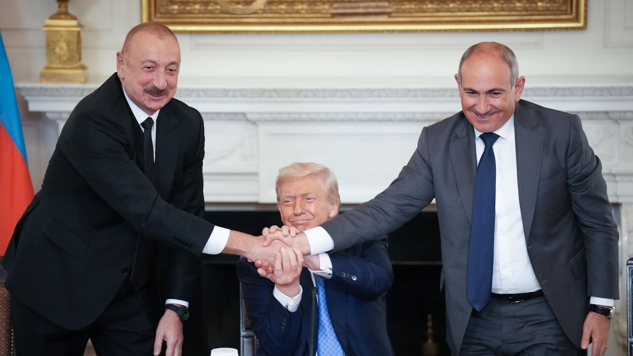  US President Donald Trump (C) joins hands with Azerbaijani President Ilham Aliyev (L) and Armenian Prime Minister Nikol Pashinyan (R) during a signing ceremony in the State Dining Room of the White House, Washington, DC, Aug. 8, 20