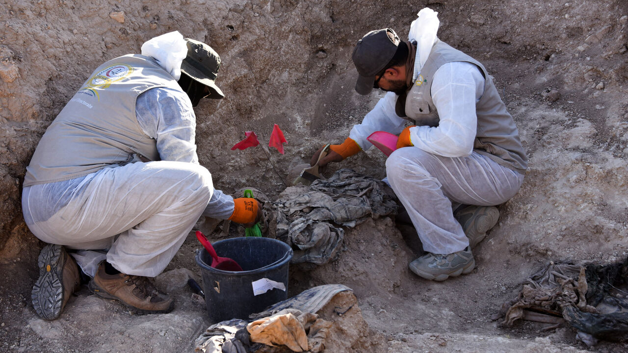 Workers dig out human remains at the Khasfa site near the northern Iraqi city of Mosul, where authorities have begun excavating a mass grave believed to contain thousands of victims of the Islamic State (IS) on Aug. 17, 2025. 