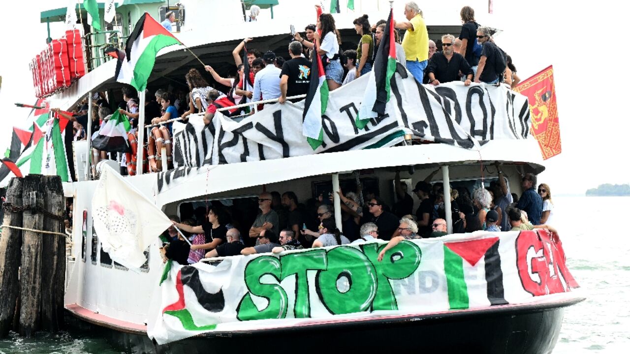 People aboard a boat wave Palestinian flags as they arrive to take part in a demonstration in support of Gaza at the Venice Lido 
