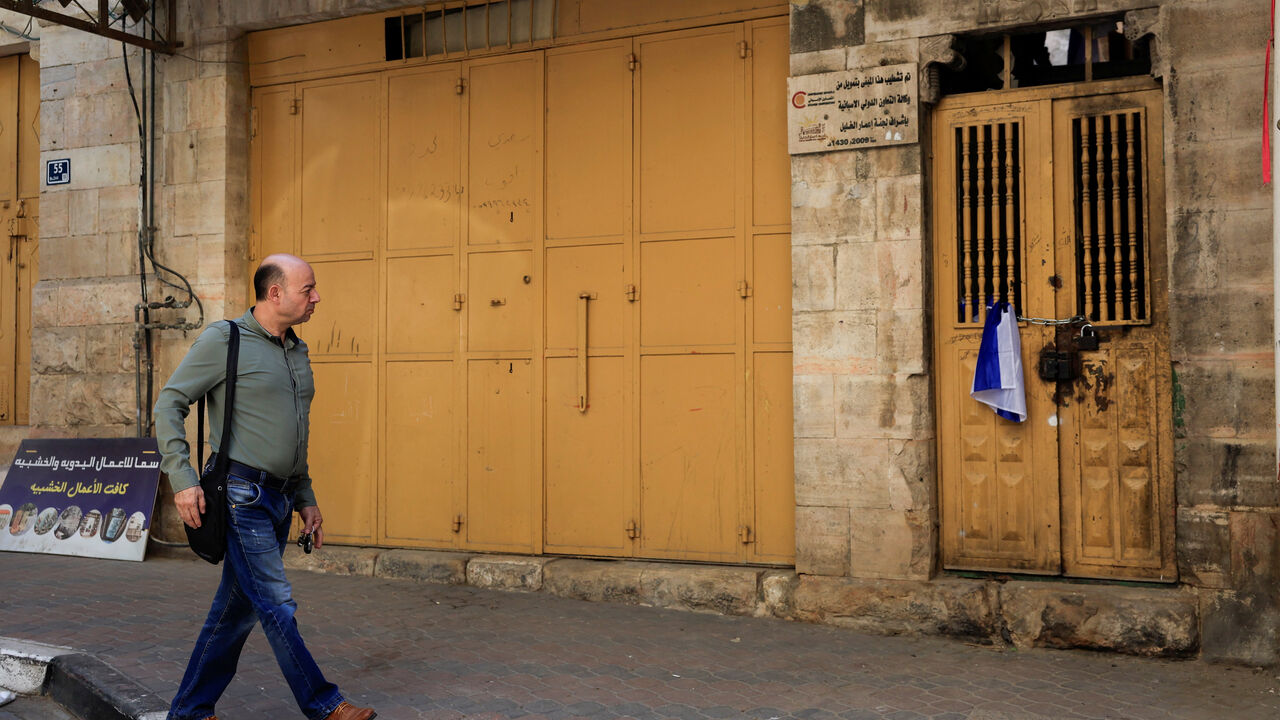 A Palestinian walks next to an Israeli flag placed on the door of a house which was taken over by Israeli settlers in the old city, in Hebron in the Israeli-occupied West Bank September 3,2025. REUTERS/Mussa Qawasma