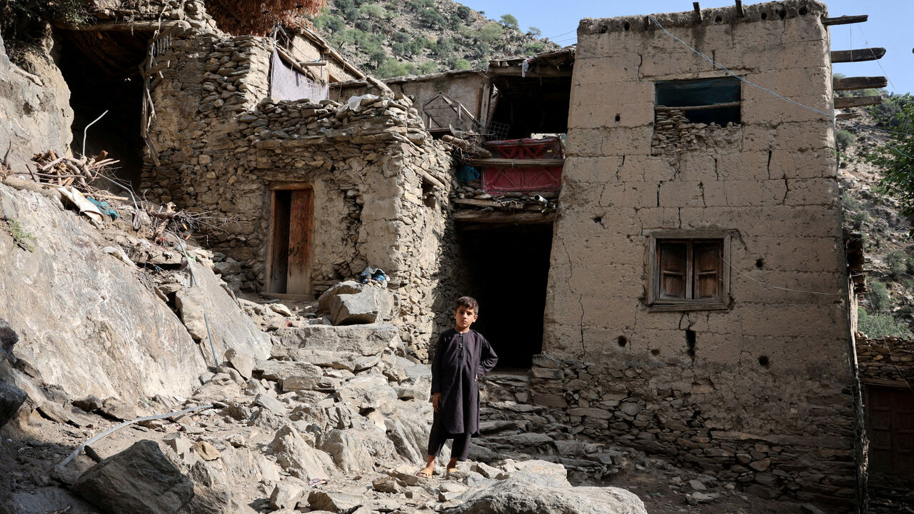 A boy stands in front of houses damaged by a deadly earthquake that struck Afghanistan's Kunar and Nangarhar provinces, at Masud village in Nurgal district, Kunar province, Afghanistan, September 4, 2025. REUTERS/Sayed Hassib