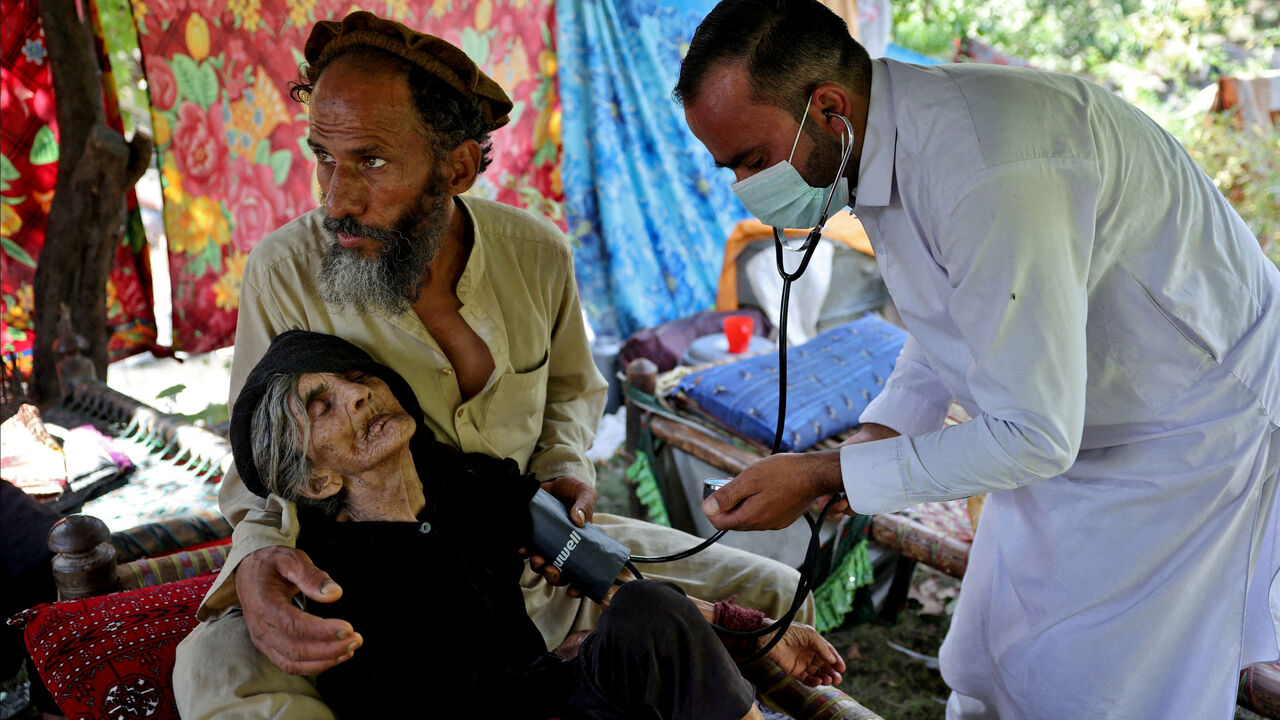 FILE PHOTO: A doctor tends to Rad Bibi, an injured Afghan woman who claims to be 110-years-old, outside her damaged house following a deadly earthquake that struck Afghanistan's Kunar and Nangarhar provinces, in Nurgal district, Kunar province, Afghanistan, September 4, 2025. REUTERS/Sayed Hassib/File Photo