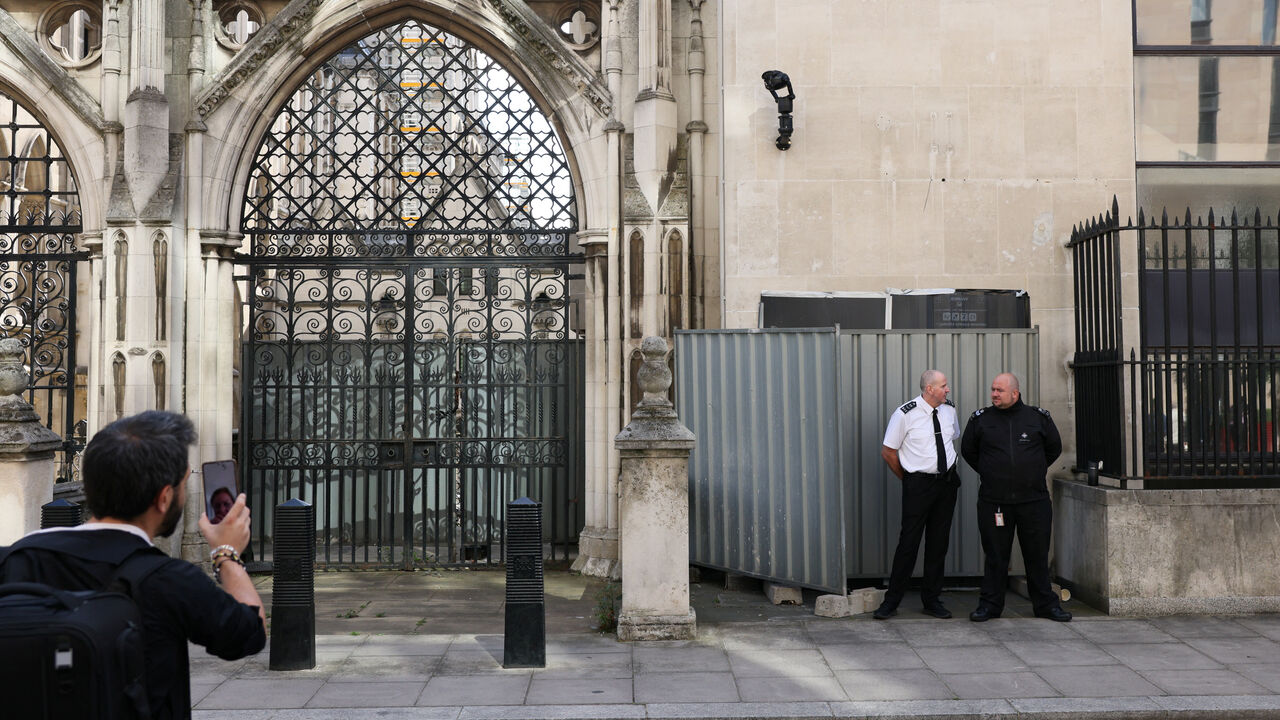 Security guards stand in front a screen covering a new mural by anonymous artist Banksy on the Royal Courts of Justice in London, Britain, September 8, 2025. REUTERS/Jack Taylor