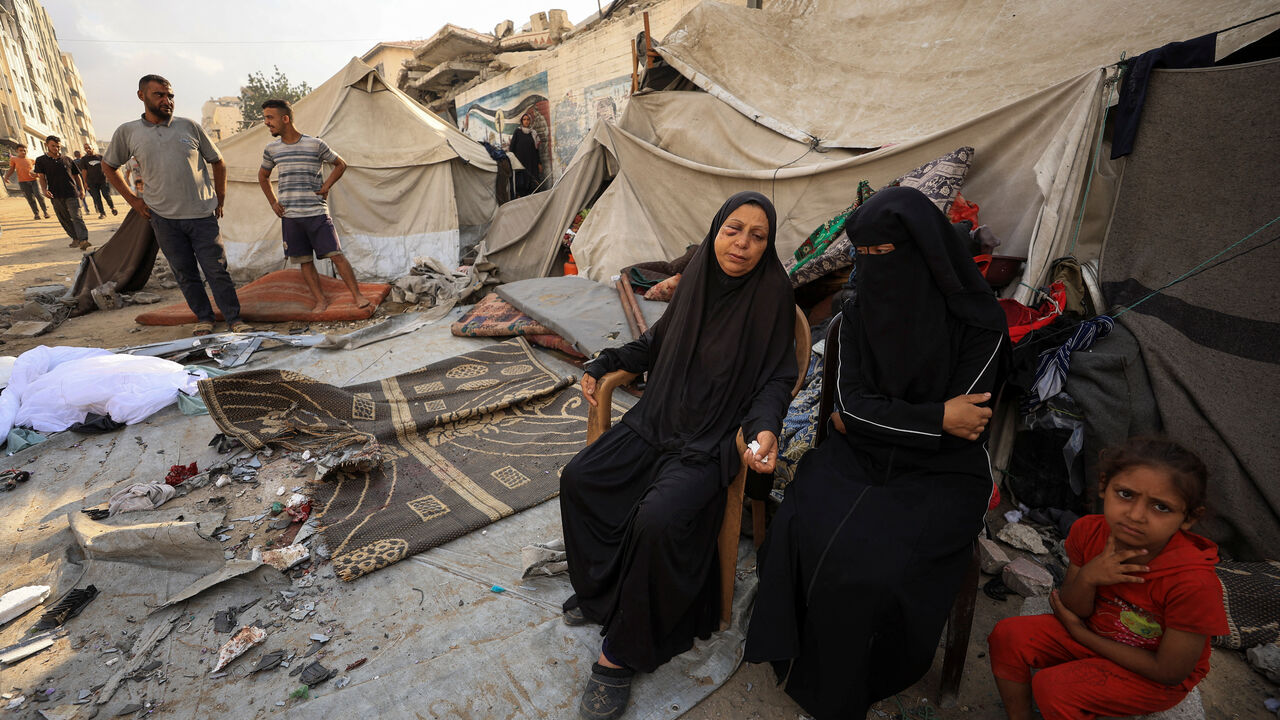 FILE PHOTO: Palestinians women and a girl sit while others inspect the site of an overnight Israeli strike on a tent, in Gaza City, September 7, 2025. REUTERS/Dawoud Abu Alkas/ File Photo