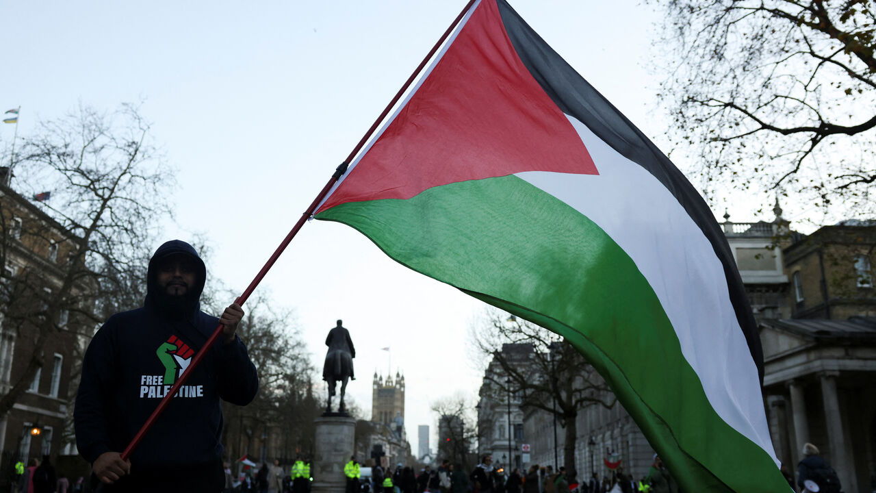 FILE PHOTO: A person holds a Palestinian flag during a protest in solidarity with Palestinians in Gaza, amid the ongoing conflict between Israel and the Palestinian Islamist group Hamas, in London, Britain, December 9, 2023. REUTERS/Hollie Adams/File Photo