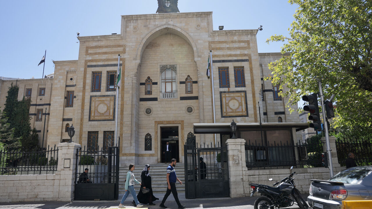 A group of civilians walk past the main gate of the Syrian parliament building, in Damascus, Syria September 3, 2025. REUTERS/Khalil Ashawi/File Photo
