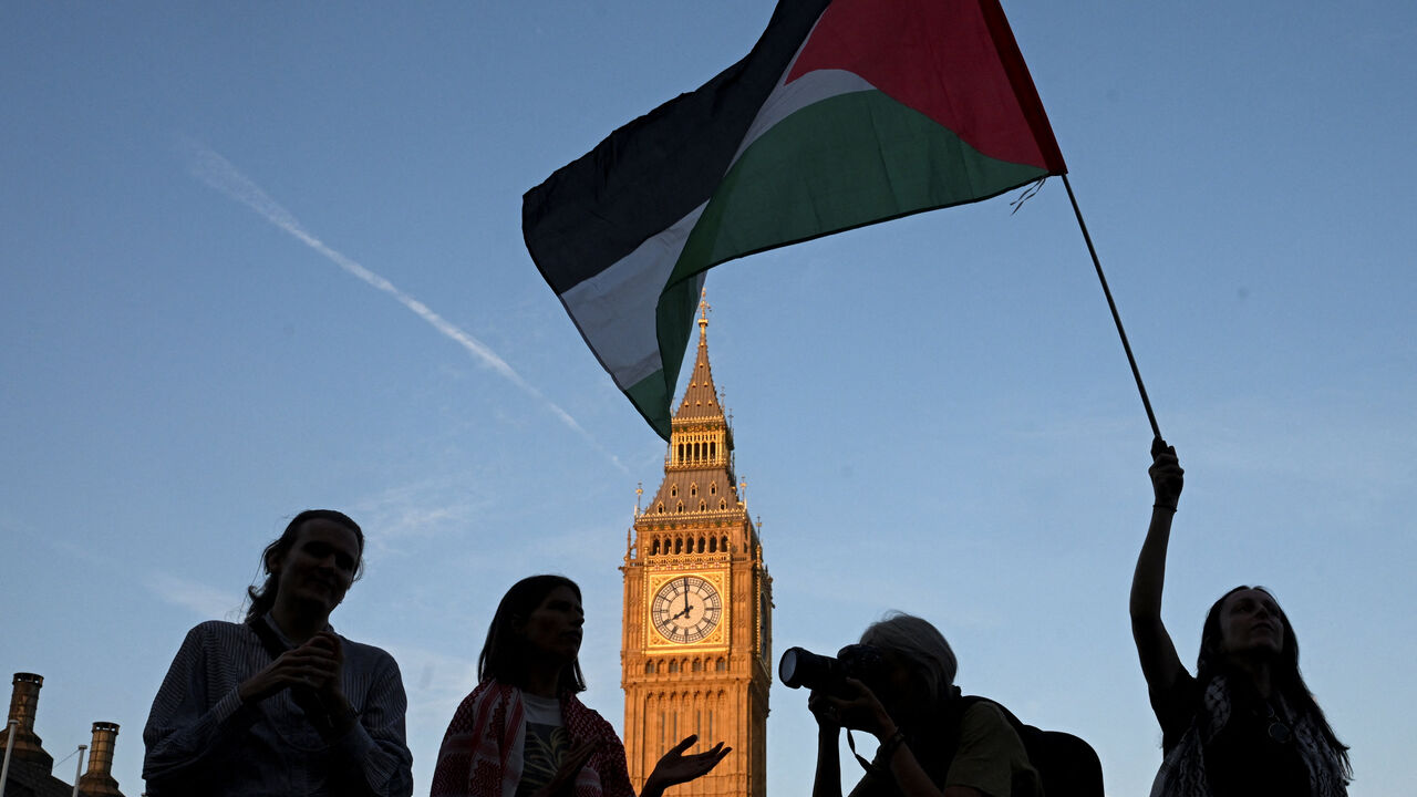 FILE PHOTO: A woman holds a Palestinian flag as demonstrators attend a rally organised by Defend Our Juries, challenging the British government's proscription of "Palestine Action" under anti-terrorism laws, in Parliament Square, in London, Britain, August 9, 2025. REUTERS/Jaimi Joy/ File Photo