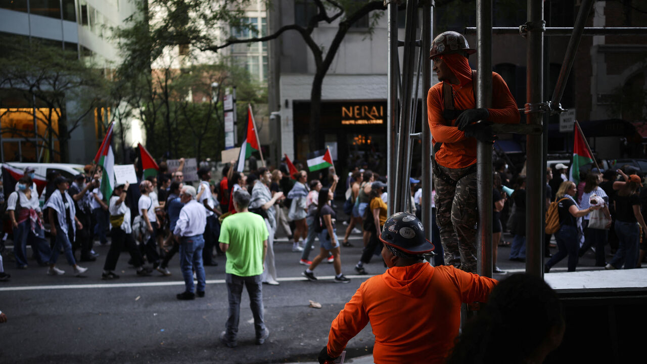 Construction workers look at people protesting against Israeli Prime Minister Benjamin Netanyahu after he delivered an address at the 80th United Nations General Assembly (UNGA) at the U.N. headquarters in New York, U.S., September 26, 2025. REUTERS/Carlos Barria
