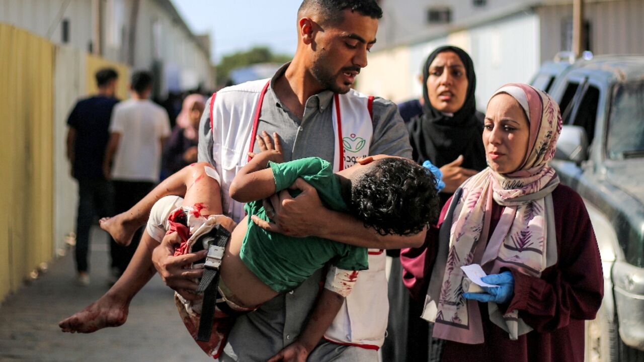 A worker at al-Awda Hospital carries a child who was injured by reported Israeli bombardment on al-Bureij September 21, 2025