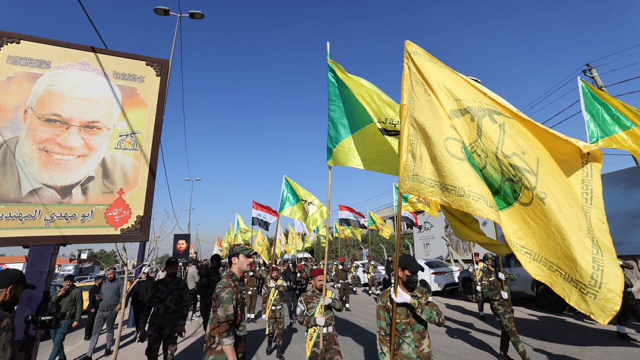 Fighters lift flags of Iraq and paramilitary groups, including al-Nujaba and Kataib Hezbollah, during a funeral in Baghdad for five militants killed a day earlier in a US strike in northern Iraq, on Dec. 4, 2023.
