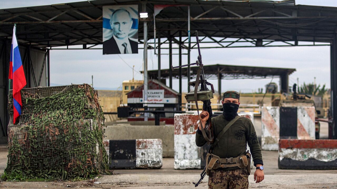 A Syrian rebel fighter looks on as he stands at an inspection checkpoint for incoming vehicles at the entrance of the Russian-leased Syrian military base of Hmeimim in Latakia province in western Syria on Dec. 29, 2024. 