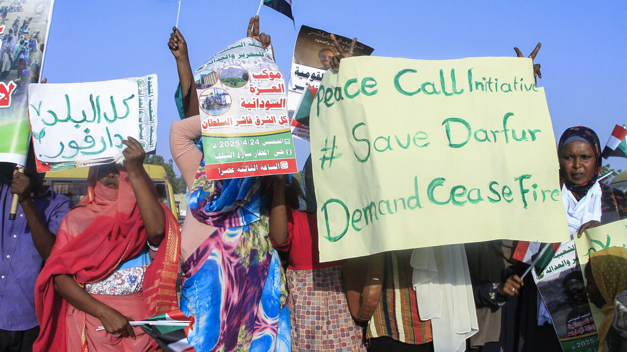 People lift national flags and placards during a rally called for by Sudan's Popular Front for Liberation and Justice in Port Sudan on April 24, 2025, to denounce the siege imposed by the paramilitary Rapid Support Forces (RSF) on El-Fasher city and express support for its residents. 