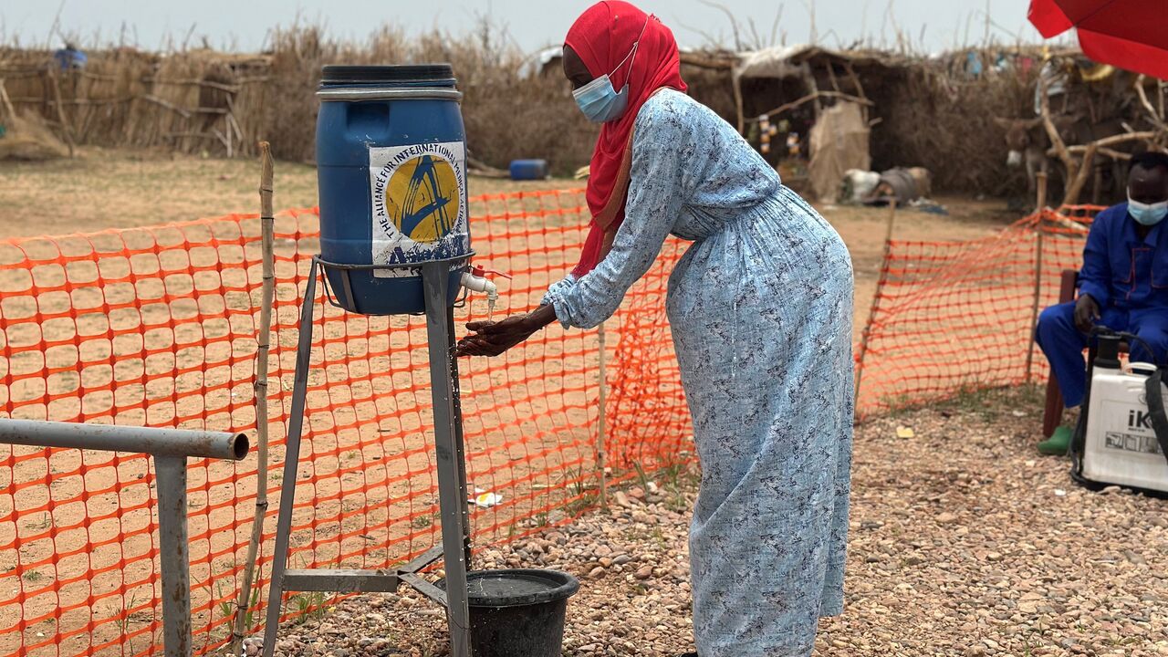 A woman washes her hands at the entrance of a cholera isolation center at the refugee camps of western Sudan, in Tawila in Darfur, on Aug. 12, 2025. 