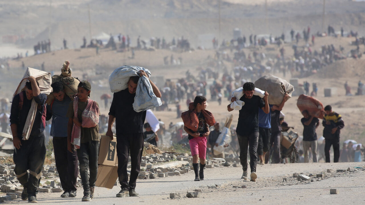 Palestinians walk with bags of humanitarian aid they received at a distribution centre run by the US and Israeli-backed Gaza Humanitarian Foundation (GHF), at the so-called "Netzarim corridor", in Nuseirat in the central Gaza Strip, on Sept. 26, 2025.