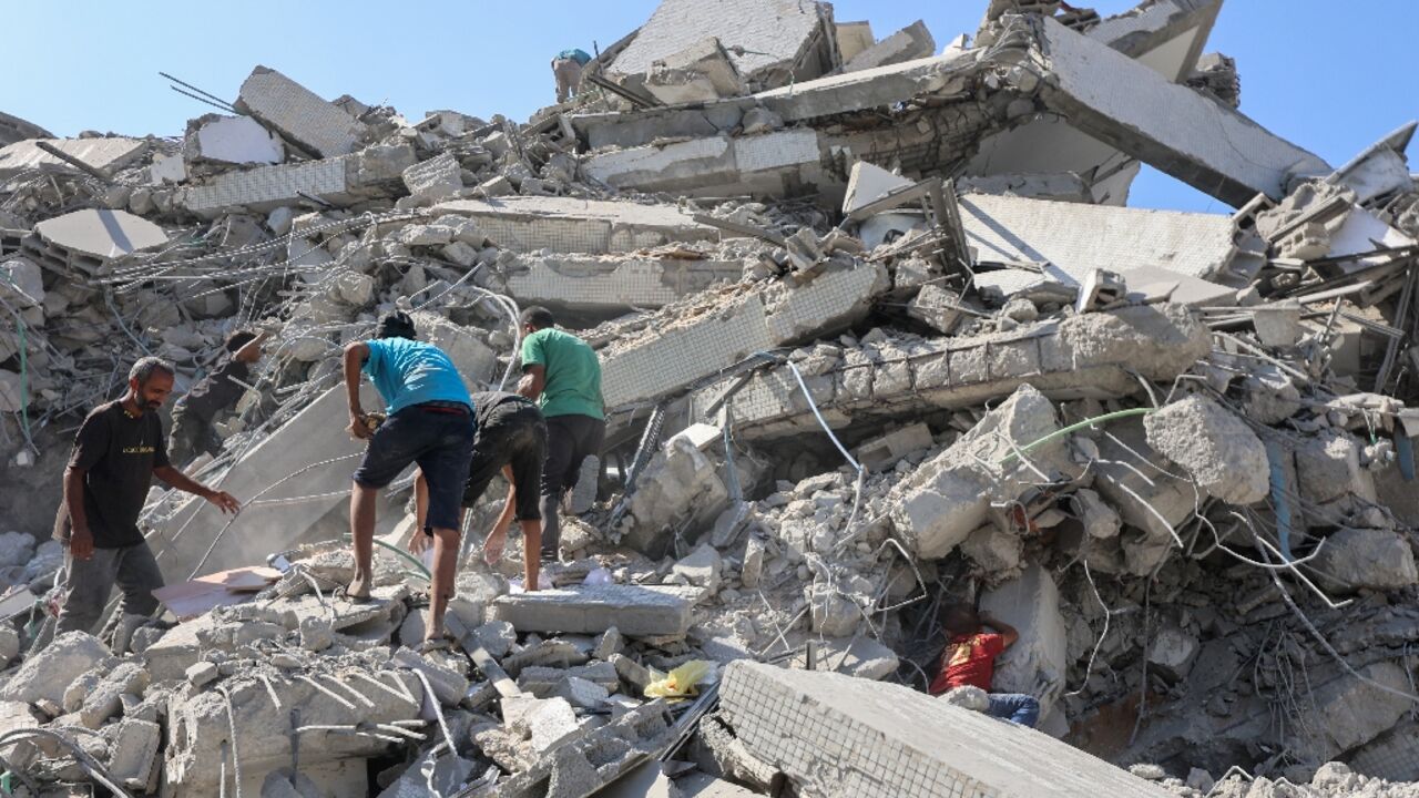 Palestinians search the rubble of al-Ghafari tower after its destruction by Israeli airstrikes in Gaza City on September 15, 2025. 