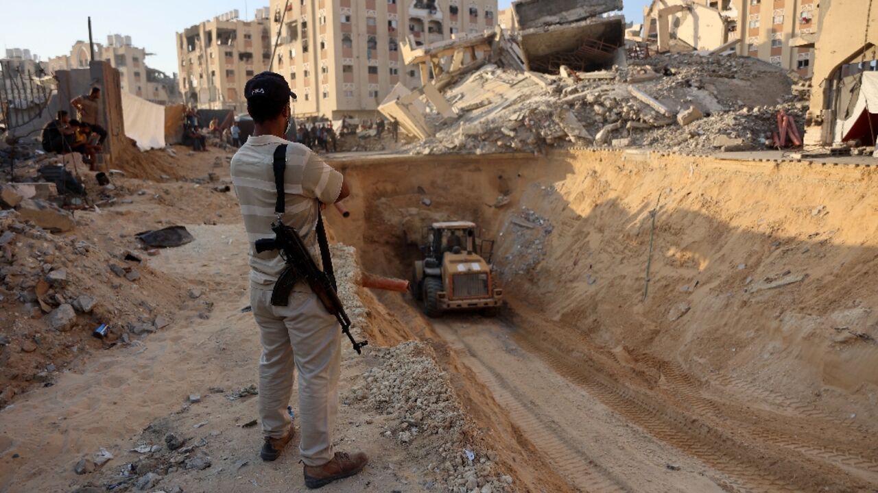 An armed Palestinian man looks at an excavator reportedly digging for the bodies of Israeli hostages