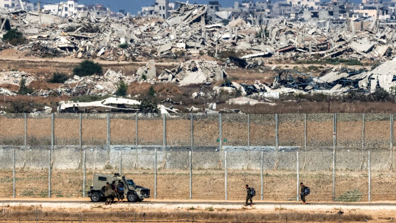 Israeli army soldiers walk towards an armoured vehicle at a position along the border fence with the Gaza Strip in southern Israel 