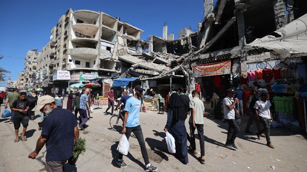 Palestinians walk past a destroyed building in Gaza's Nuseirat refugee camp