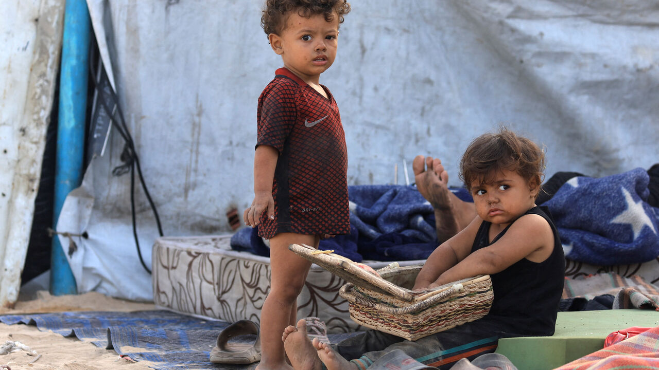 Displaced Palestinian children shelter on the side of a raod, after Hamas agreed to release hostages and accept some other terms in a U.S. plan to end the war, in the central Gaza Strip, October 4, 2025. REUTERS/Dawoud Abu Alkas