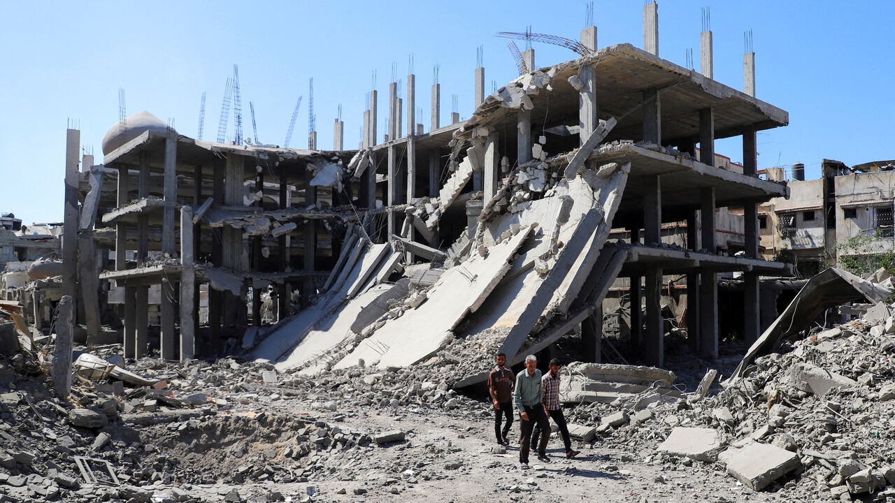 Palestinians walk past a destroyed building, as they inspect the damage in the aftermath of Israeli operation at Sabra neighbourhood in Gaza City, October 8, 2025. REUTERS/Ebrahim Hajjaj     TPX IMAGES OF THE DAY