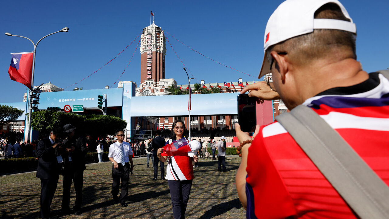 A man takes pictures of a woman posing in front of the Presidential Office building on the day President Lai Ching-te delivers a speech during National Day celebrations in Taipei, Taiwan, October 10, 2025. REUTERS/Ann Wang