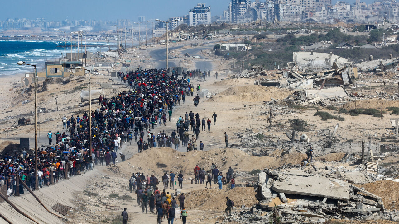 Palestinians, who were displaced to the southern part of Gaza at Israel's order during the war, walk along a road ast destroyed buildings as they attempt to return to the north after a ceasefire between Israel and Hamas in Gaza went into effect, in the central Gaza Strip, October 10, 2025. REUTERS/Mahmoud Issa
