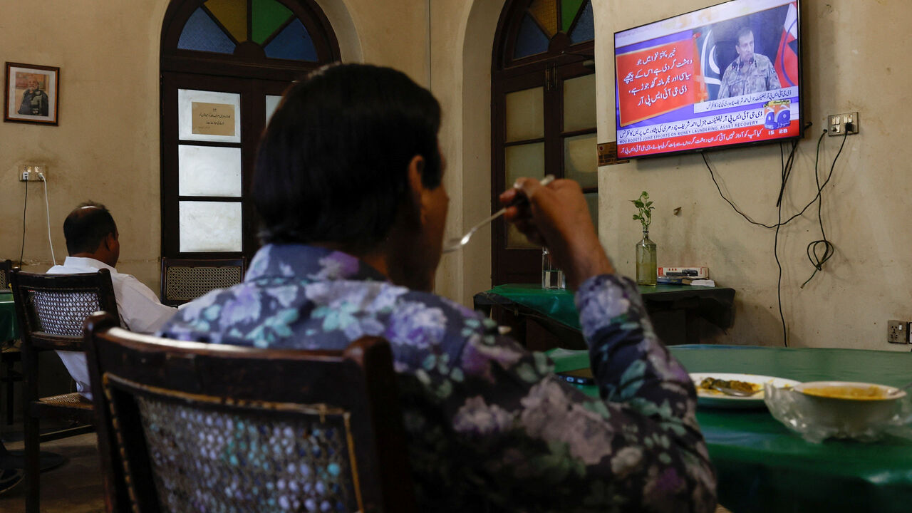 People watch a televised press briefing by Ahmed Sharif Chaudhry, Director General of the Inter-Services Public Relations wing of the Pakistan Armed Forces, in Karachi, Pakistan, October 10, 2025. REUTERS/Akhtar Soomro